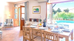 A dining area with a table set for four, a painting on the wall, and a view of a swimming pool. - Beautiful villa with spacious terrace and private swimming pool, on the Croatian island of Hvar (Hvar)