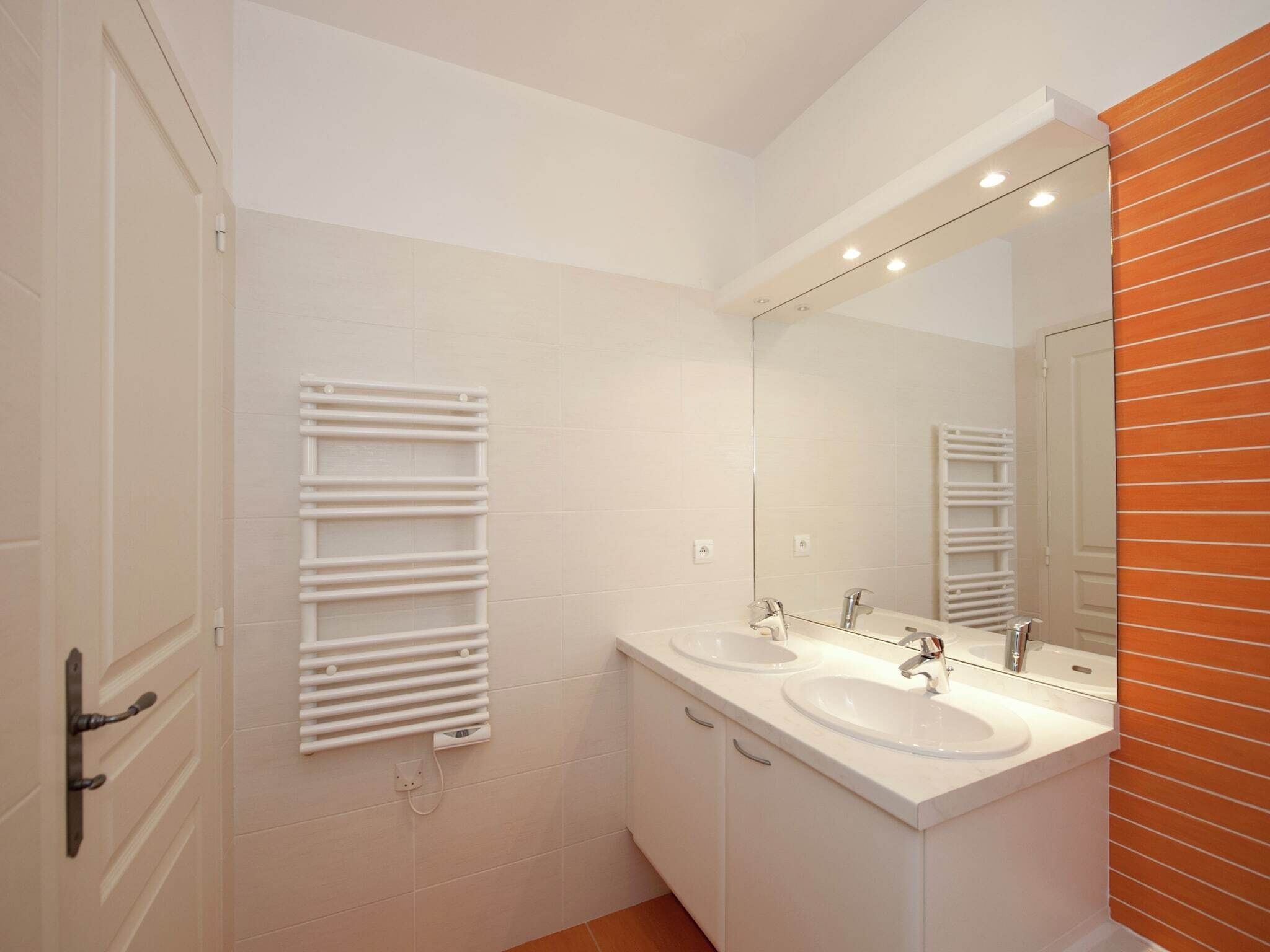 A modern bathroom with two sinks, a large mirror, and a towel rack.