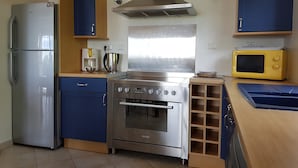 A compact kitchen with a stainless steel refrigerator, a stove, and a microwave. - Courry Views: Pool & Nature (Courry)