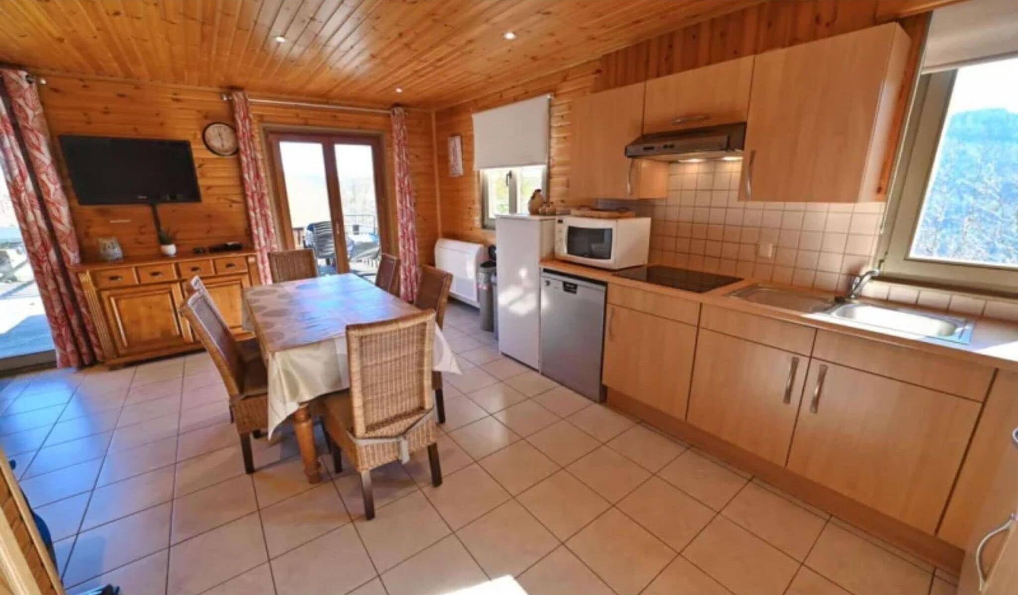 Una baita in legno con zona pranzo, cucina e televisione.