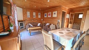 A cozy cabin-style room with a wooden interior, a sofa set, a dining table, and a fireplace. - Holiday Home in La Roche with Sauna & Views (La Roche)