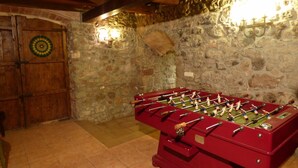 Une pièce avec une table de baby-foot, un jeu de fléchettes et un mur en pierre.