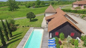 Ein großer rechteckiger Pool mit einer Holzterrasse, umgeben von blauen Liegestühlen.