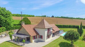 Ein zweistöckiges Haus mit Naturstein-Fassade und Ziegeldach, mit Swimmingpool.