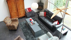 A living room with a sofa, armchair, coffee table, and a fireplace. - Holiday Home in Langweer with Infrared Sauna (Langweer)