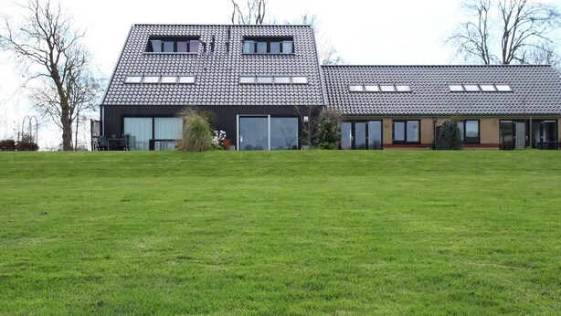 A modern two-story building with a flat roof, large windows, and a grassy lawn in front. - Holiday Home in Langweer with Infrared Sauna (Langweer)