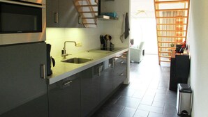 A modern kitchen with grey cabinets, a Siemens oven, a stainless steel sink, and a built-in bookshelf in the adjacent living area. - Holiday Home in Langweer with Infrared Sauna (Langweer)