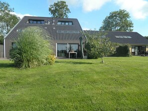 A modern house with a sloped roof, large windows, and a well-maintained lawn.