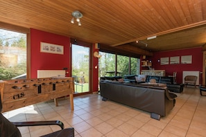 Een ruime woonkamer met een tafelvoetbaltafel, een bank en een open haard.