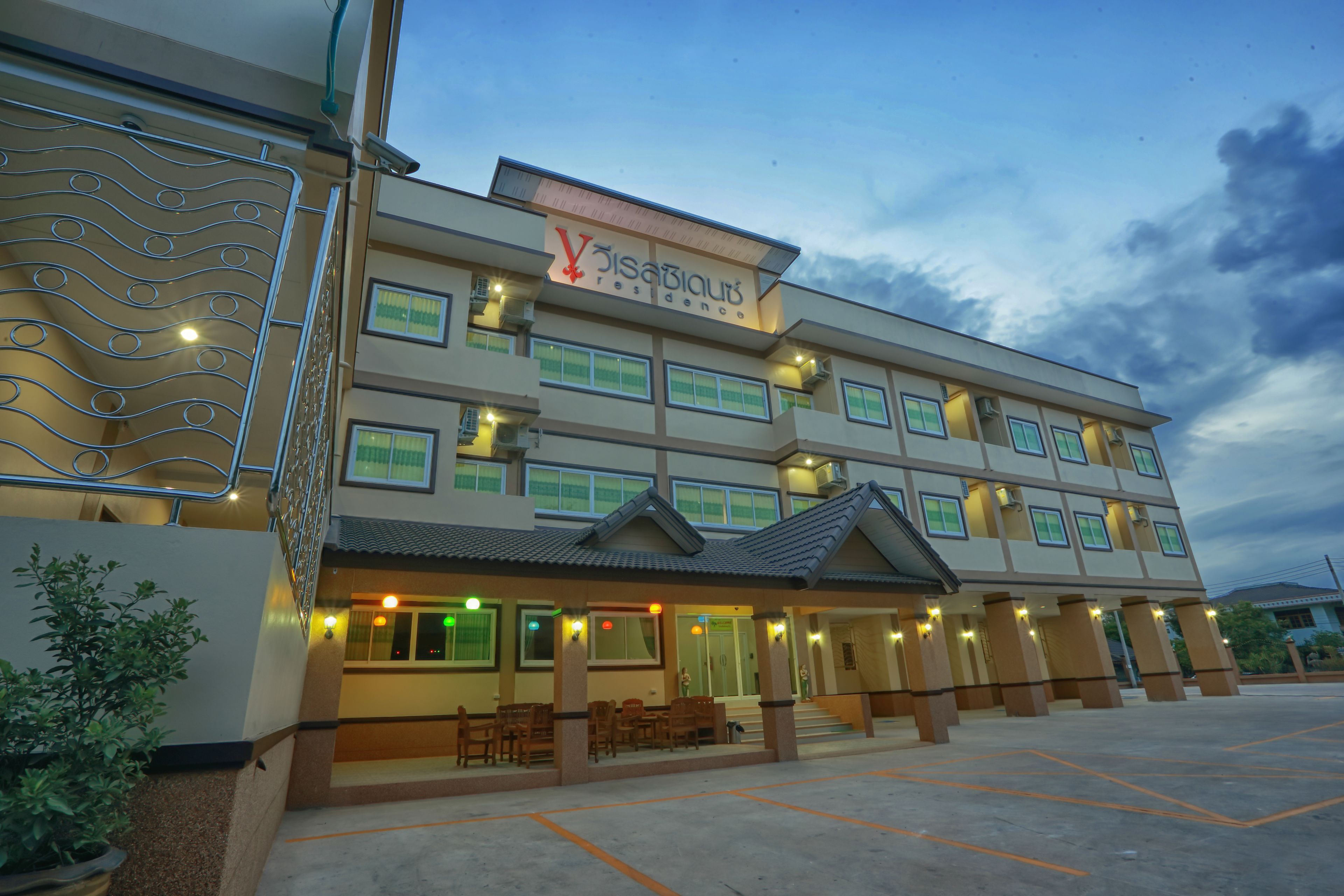 A multi-story hotel with a sign reading "Villasiaub Residence." It features a covered entrance with seating and a parking lot in front.