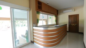 A reception area with a curved reception desk, sliding glass doors, and a wooden door. - V Residence (Nakhon Ratchasima)
