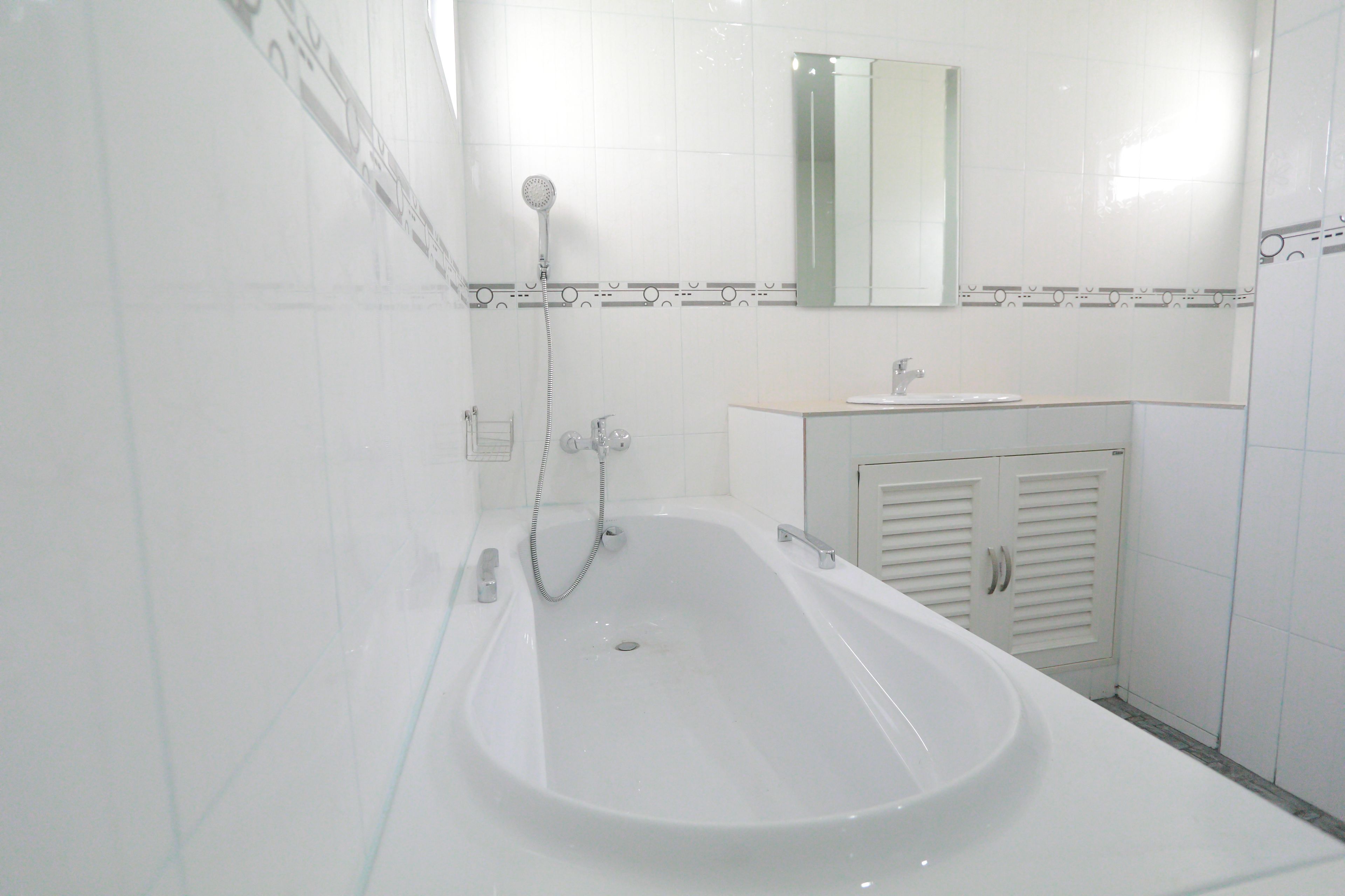 A bathroom with a bathtub, a sink, and a mirror.