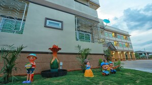 A hotel with a large, modern building facade, a decorative fountain, and a well-maintained lawn. - V Residence (Nakhon Ratchasima)