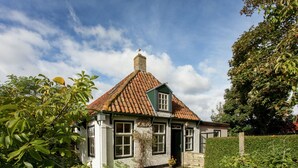Une charmante maison avec un toit en tuiles, des murs blancs et une porte verte.