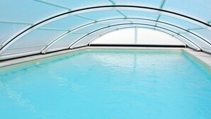 Ein Innenpool mit klarer Glasdecke und Fliesenboden.
