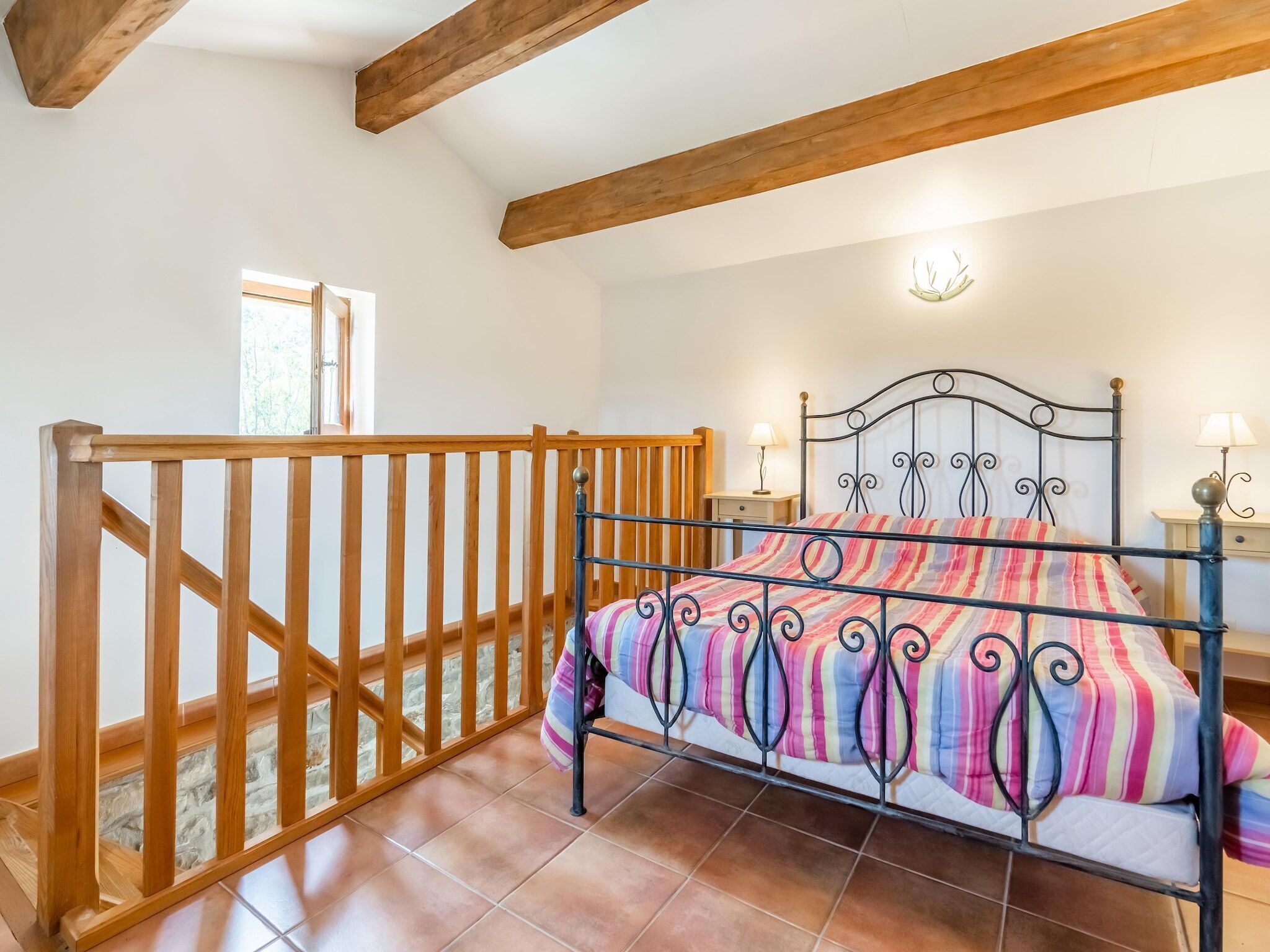 Une chambre à coucher avec un lit, une rambarde en bois et une fenêtre.