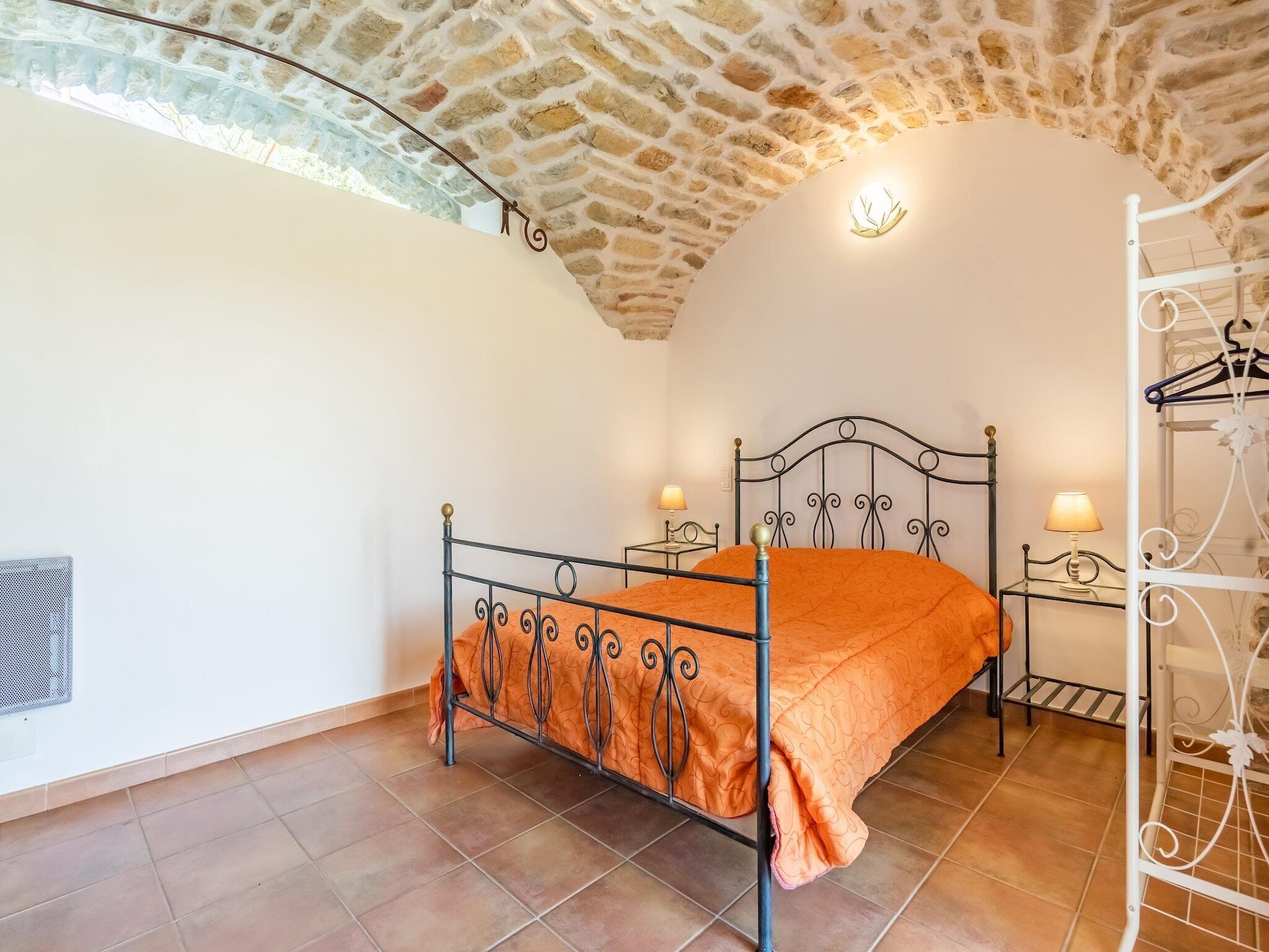 A bedroom with a stone ceiling, a metal bed frame, and two bedside tables with lamps.