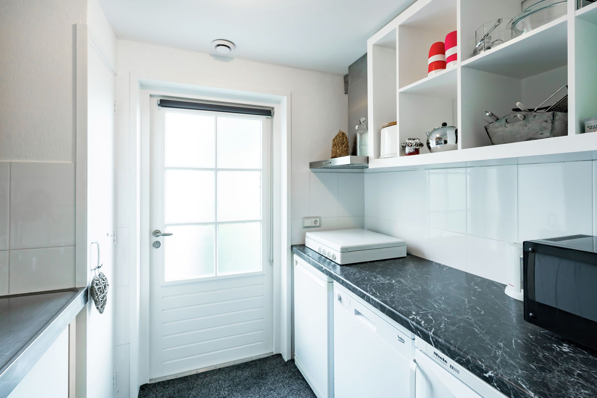 A compact kitchen with white cabinets, a black countertop, and a microwave.