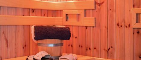 Banco de madera en un sauna, con una toalla y zapatillas.