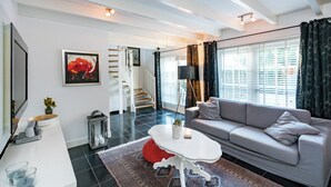 A modern living room with a grey sofa, a white coffee table, and a staircase leading to an upper floor. - Cottage in Ovezande with terrace (Ovezande)