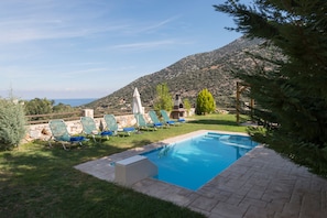 A swimming pool with lounge chairs and a stone patio.
