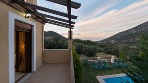 Ein Balkon mit Blick auf einen Pool und Liegestühle, einer Pergola und einer Tür zu einem Zimmer.