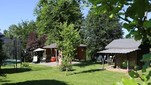 Ein Garten mit Trampolin, Schaukel und einer kleinen Holzkonstruktion.