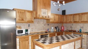A kitchen with wooden cabinets, a stainless steel refrigerator, a microwave, and a checkered island.