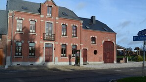 A red brick building with a large wooden door and multiple windows.