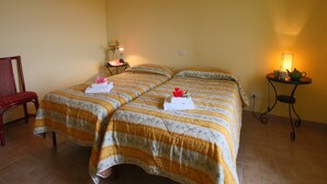 Une chambre avec deux lits, une chaise, une petite table avec une lampe et un luminaire fixé au mur.