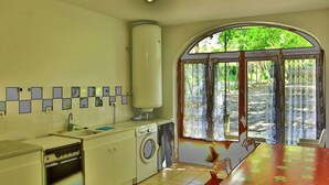 A compact kitchen with a washing machine, a sink, and a table with a floral tablecloth.