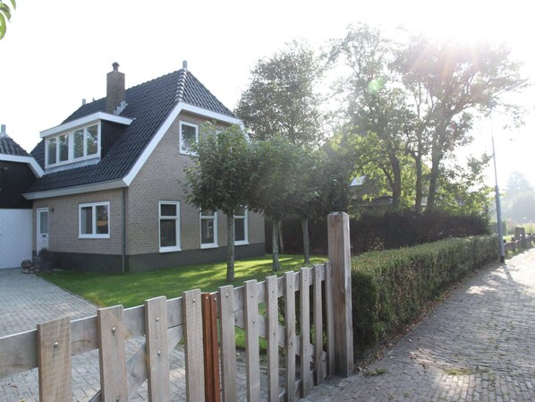 A residential house with a sloped roof, a front lawn, and a wooden fence.
