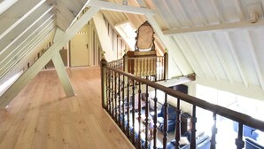 A wooden staircase with a railing leading to a second-floor area with a view of the outdoors. - Holiday Home in Saint-Omer near Lake & Forest (Saint-Omer (Serques))