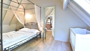 A bedroom with a four-poster bed, a nightstand, and a window with a view of a staircase. - Holiday Home in Saint-Omer near Lake & Forest (Saint-Omer (Serques))