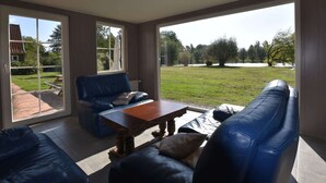 A spacious living room with a large sliding glass door leading to a grassy outdoor area. - Holiday Home in Saint-Omer near Lake & Forest (Saint-Omer (Serques))