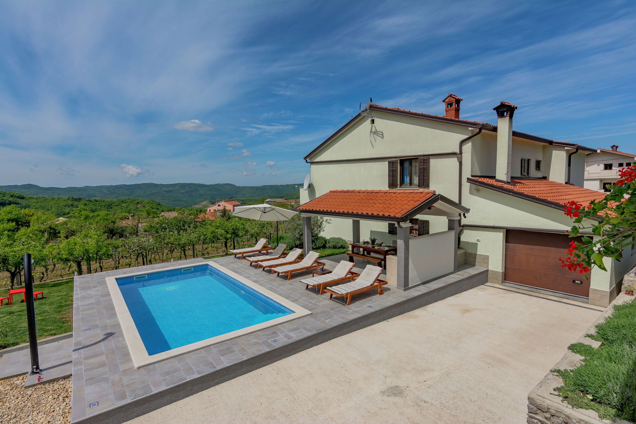 A poolside area with a swimming pool, lounge chairs, and a view of the surrounding landscape.