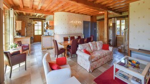 A spacious living area with a wooden ceiling, a dining table, and a sofa. - Elegant Villa in Saint-Médard (St. Medard D'excideuil)