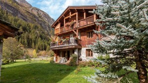 A wooden chalet with a balcony, surrounded by a lush green lawn and a mountain backdrop. - Lake-view chalet in Tignes, close to ski area (Tignes)