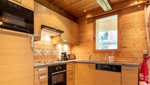 A modern kitchen with wooden cabinetry, a built-in oven, a dishwasher, and a window with a view of the outdoors. - Lake-view chalet in Tignes, close to ski area (Tignes)