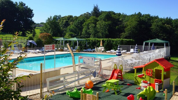 A swimming pool with a fenced area, lounge chairs, and a children's play area with slides and toys. - Family Getaway in Dordogne (Gavaudun)