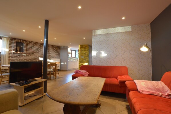 Una sala de estar moderna con un televisor de pantalla plana, una mesa de centro de madera y un sof á rojo.