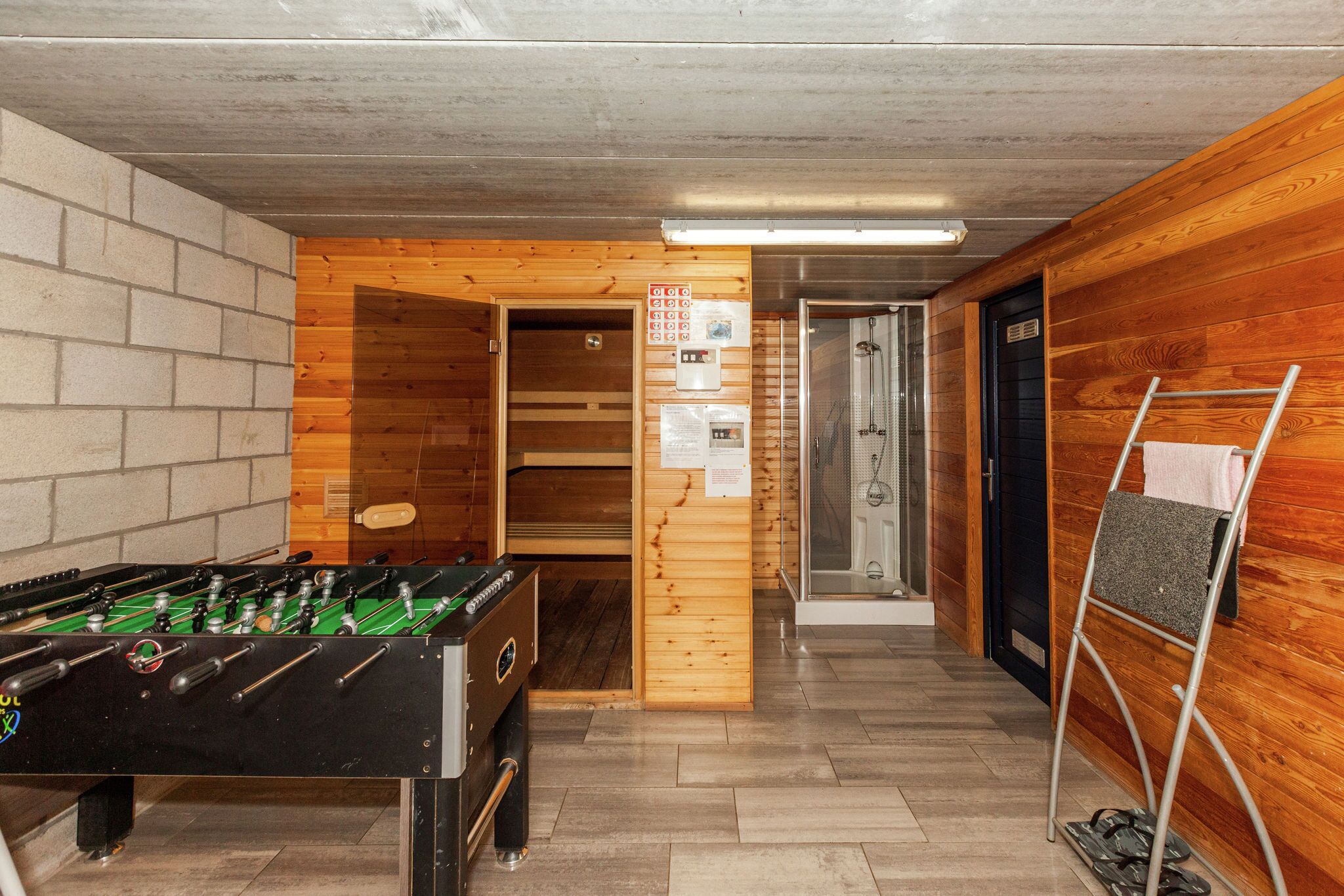 Una habitación con mesa de futbolín, sauna y zona de ducha.