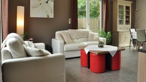 A modern living room with a white sofa, red ottomans, and a dining area with a table and chairs. - Elegant Villa in Bomal (Bomal-Sur-Ourthe)