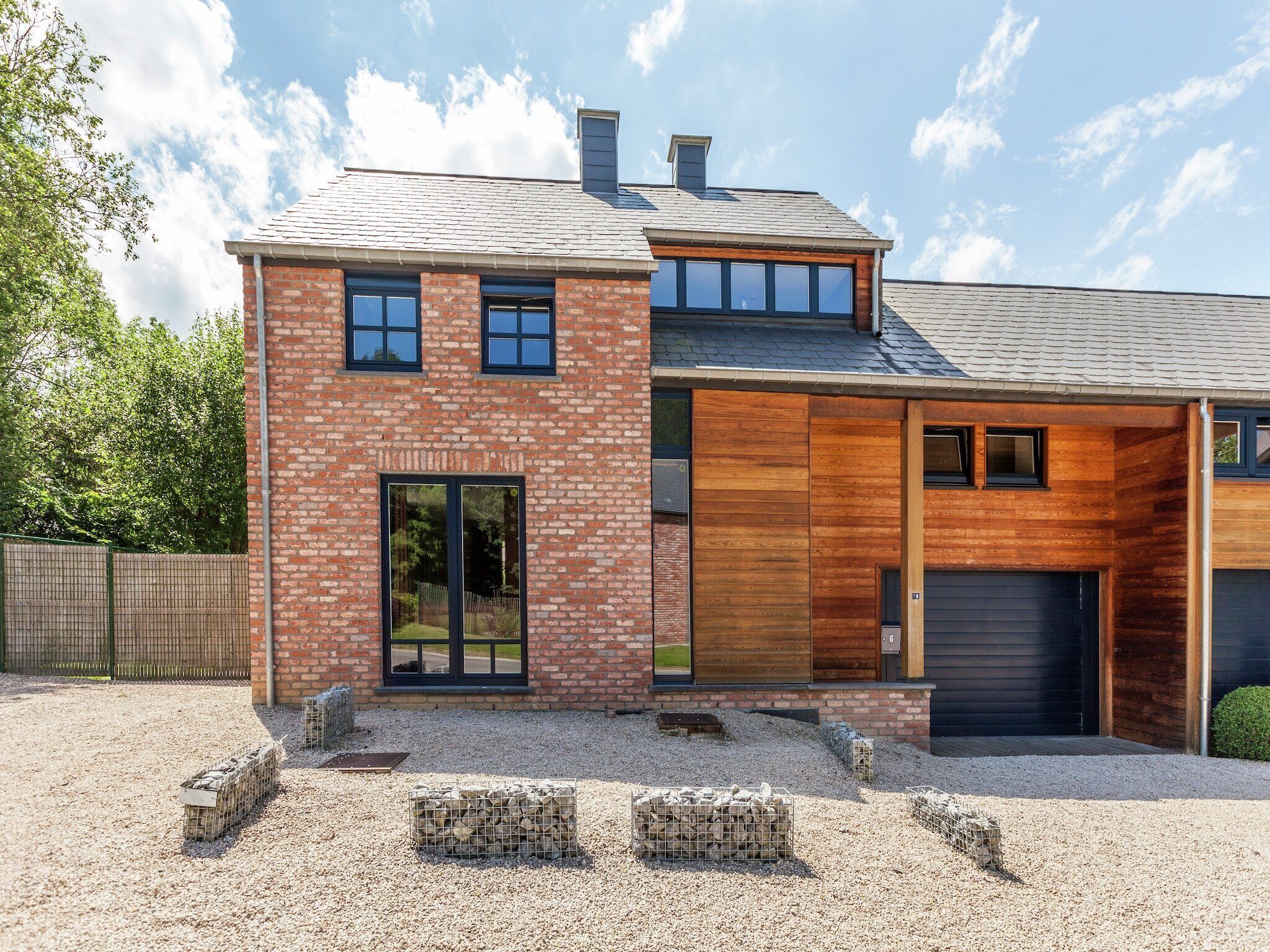 A modern two-story house with a brick facade, large windows, and a garage.