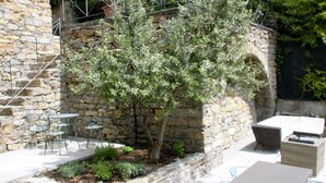 A stone building with outdoor seating, including tables and chairs, and a small tree in the center. - Rustic Tuscan Cottage (Fivizzano)