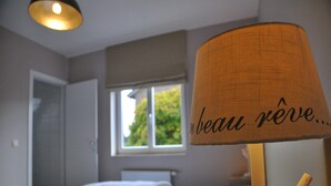 Une chambre à coucher avec un lit, une fenêtre et une lampe dotée d’un abat-jour en tissu.