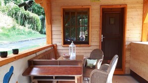 Una cabana de fusta amb una cadira, cadires de vimet i una finestra, i una porta.