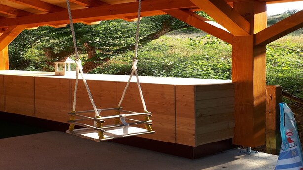 Una construcció de fusta amb una plataforma elevada i cadenes per a balancejar-se.