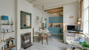 A cozy dining area with a fireplace, wooden chairs, and a table set for four. - Picturesque fisherman's house near the beach (Scheveningen)