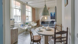A cozy dining area with a round table, chairs, and a hanging light fixture. - Picturesque fisherman's house near the beach (Scheveningen)